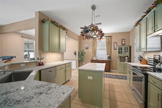 kitchen with light stone counters, a center island, green cabinetry, and appliances with stainless steel finishes