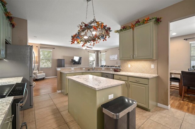 kitchen with kitchen peninsula, a center island, light hardwood / wood-style floors, and appliances with stainless steel finishes