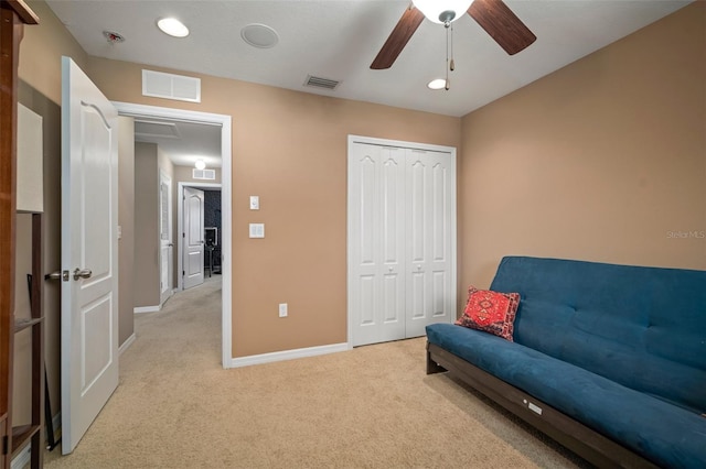 living area with light carpet and ceiling fan