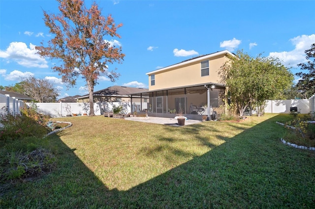 back of property with a sunroom, a patio area, and a lawn