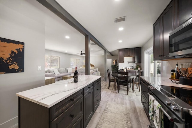 kitchen featuring appliances with stainless steel finishes, dark brown cabinetry, ceiling fan, a center island, and light hardwood / wood-style floors