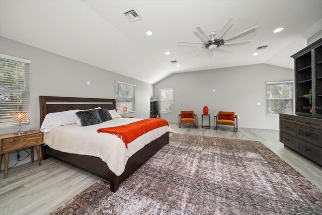 bedroom featuring vaulted ceiling, light hardwood / wood-style flooring, multiple windows, and ceiling fan