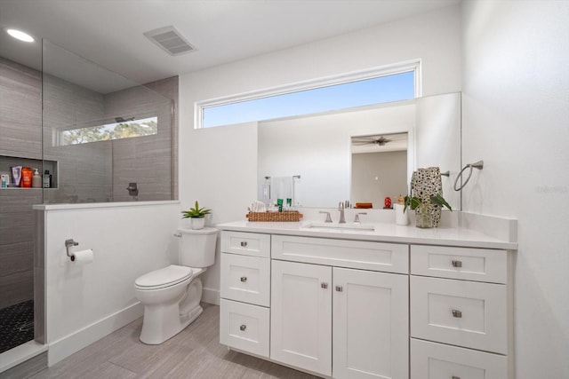 bathroom featuring vanity, toilet, and a tile shower