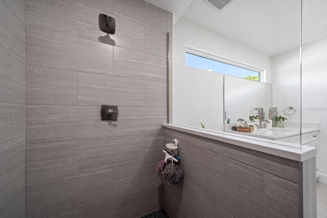 bathroom featuring a tile shower and vanity