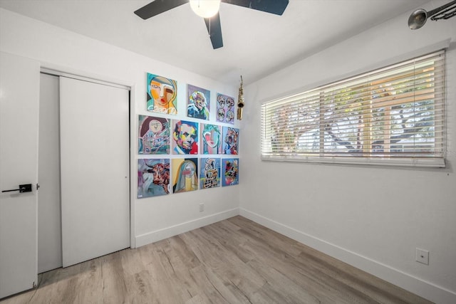 unfurnished bedroom with ceiling fan, a closet, light wood-type flooring, and multiple windows