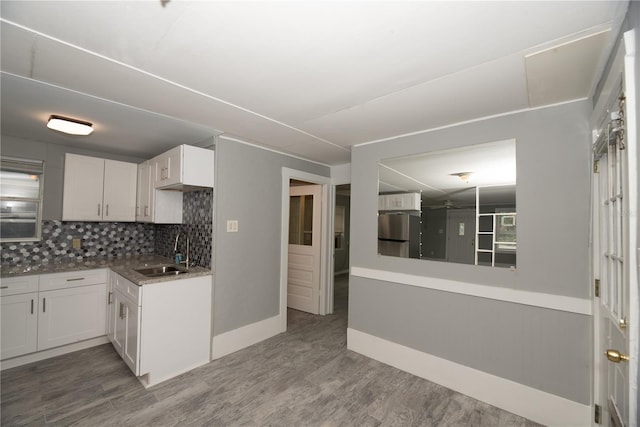 kitchen featuring stainless steel refrigerator, sink, hardwood / wood-style floors, decorative backsplash, and white cabinets