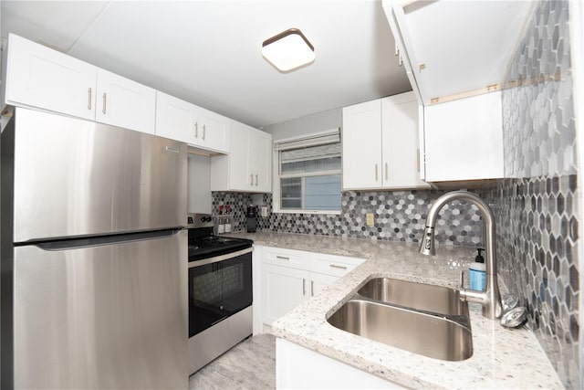 kitchen featuring decorative backsplash, appliances with stainless steel finishes, light stone counters, sink, and white cabinetry