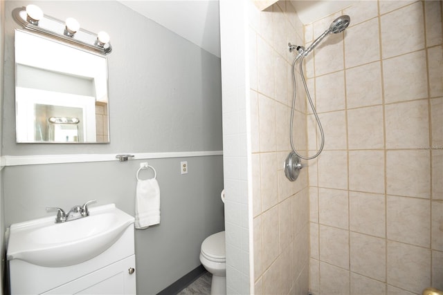 bathroom featuring tiled shower, vanity, and toilet