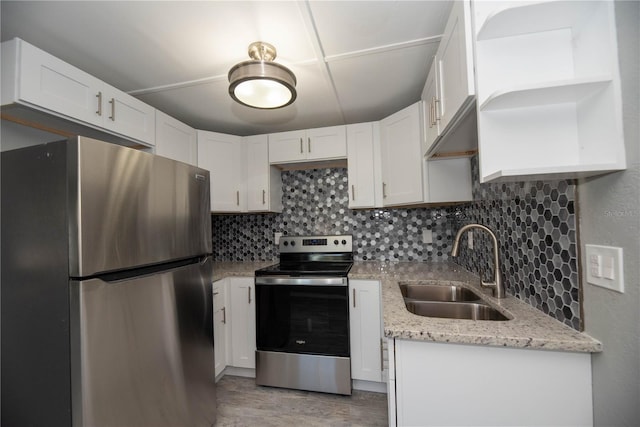 kitchen with light stone counters, sink, white cabinets, and appliances with stainless steel finishes