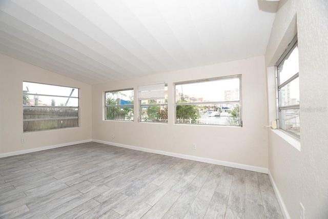 spare room featuring light hardwood / wood-style floors and vaulted ceiling