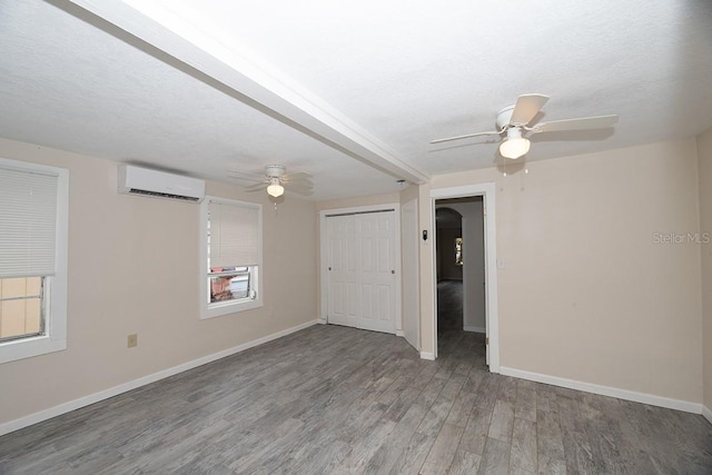 spare room featuring hardwood / wood-style flooring, ceiling fan, an AC wall unit, and a textured ceiling