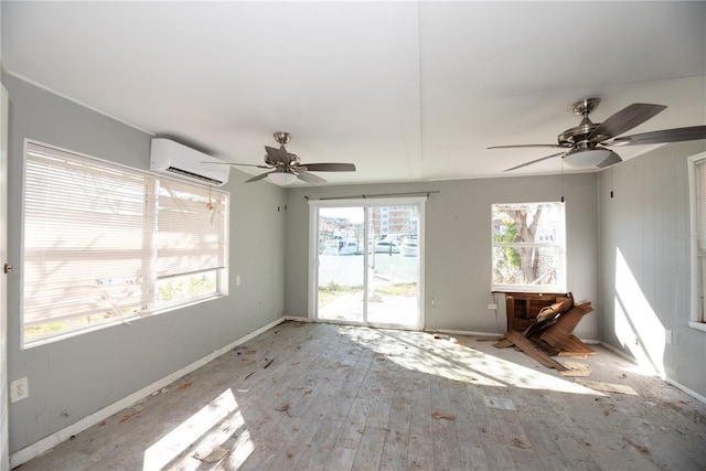 spare room featuring ceiling fan, light hardwood / wood-style flooring, and a wall mounted air conditioner