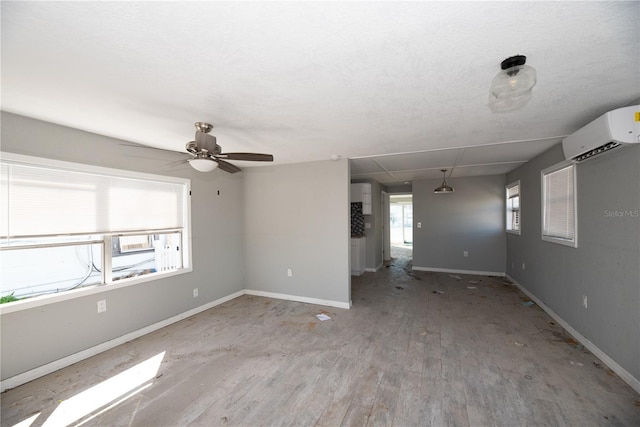 spare room with an AC wall unit, ceiling fan, and light hardwood / wood-style floors