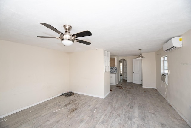 unfurnished room featuring light wood-type flooring, a wall unit AC, ceiling fan, and cooling unit