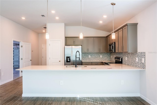 kitchen featuring kitchen peninsula, appliances with stainless steel finishes, dark hardwood / wood-style flooring, pendant lighting, and lofted ceiling