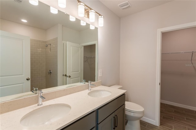 bathroom with vanity, toilet, and tiled shower