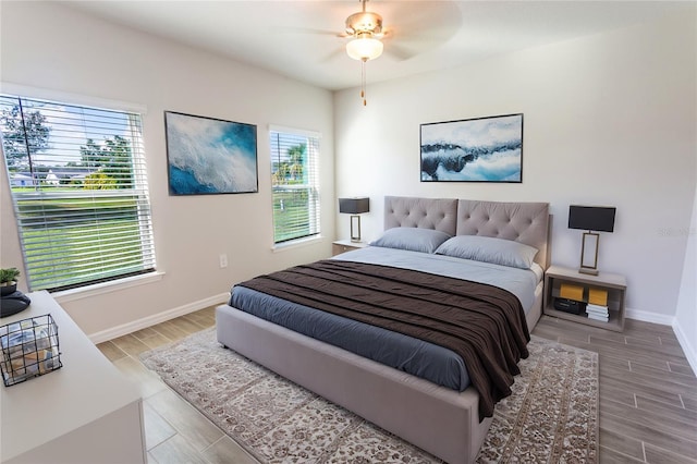 bedroom with multiple windows, ceiling fan, and hardwood / wood-style flooring