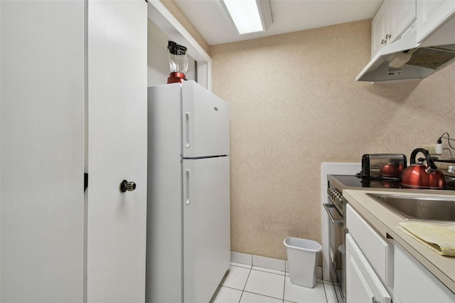 kitchen featuring white cabinets, white fridge, stainless steel electric range oven, and light tile patterned flooring