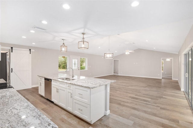 kitchen featuring white cabinetry, ceiling fan, stainless steel appliances, a barn door, and pendant lighting