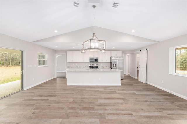 5421 N Nakoma Dr, Beverly Hills, FL 34465 - kitchen with stainless steel appliances, white cabinets, lofted ceiling, light wood finished floors, and an island with sink