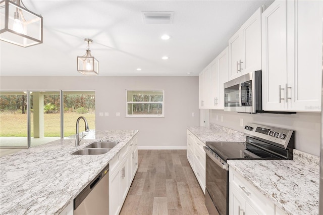 kitchen featuring pendant lighting, white cabinets, sink, light hardwood / wood-style floors, and stainless steel appliances