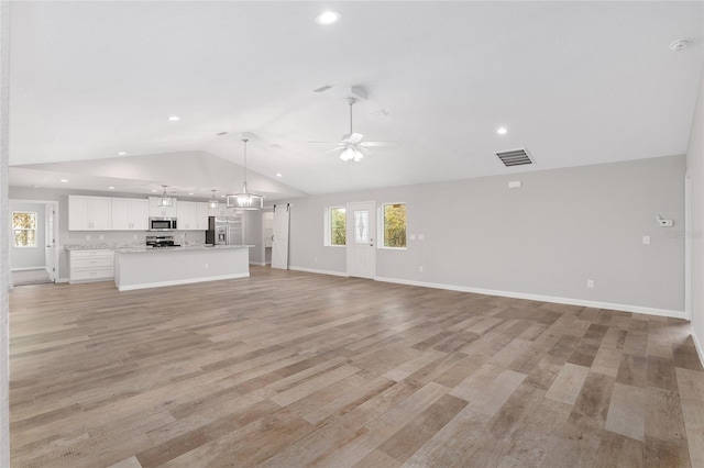 unfurnished living room featuring ceiling fan, vaulted ceiling, and light wood-type flooring