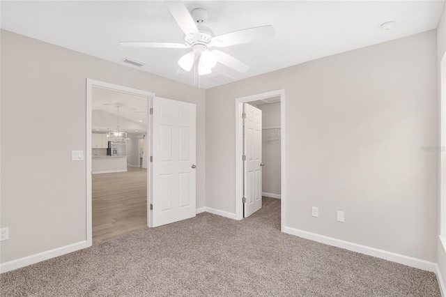 unfurnished bedroom featuring ceiling fan, a spacious closet, carpet floors, and a closet