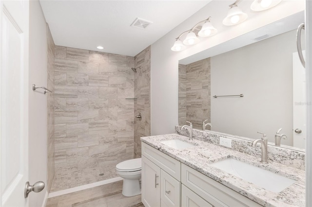 bathroom with vanity, toilet, and a tile shower