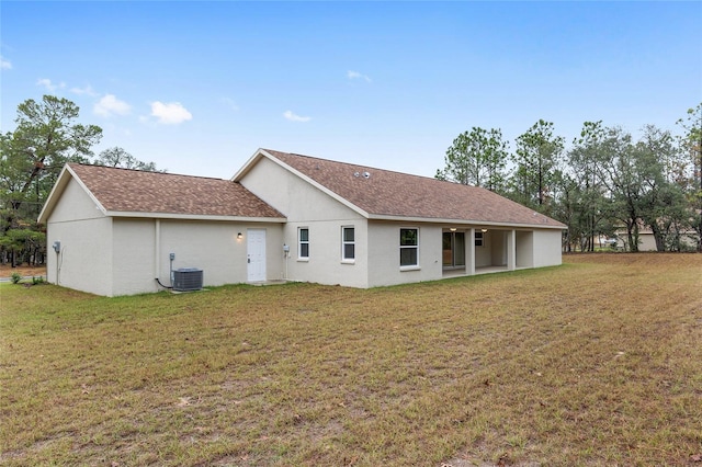 rear view of property with a lawn and central air condition unit