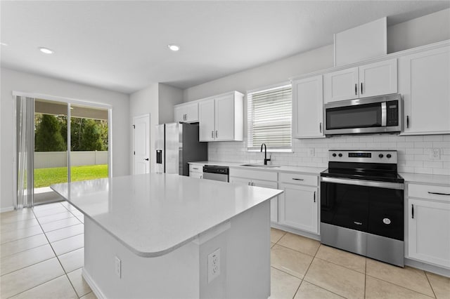 kitchen featuring appliances with stainless steel finishes, tasteful backsplash, sink, white cabinets, and a kitchen island