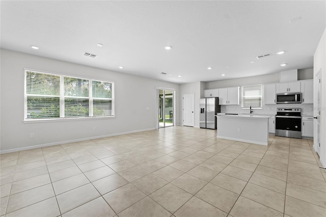 kitchen with appliances with stainless steel finishes, a center island, white cabinetry, and a healthy amount of sunlight