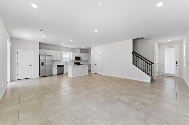 unfurnished living room featuring sink and light tile patterned flooring