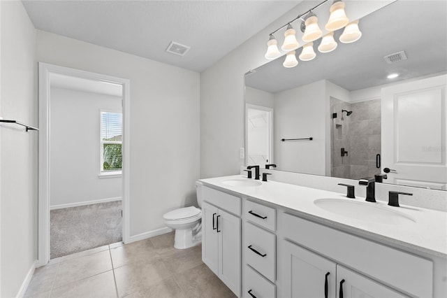 bathroom with tile patterned flooring, vanity, tiled shower, and toilet