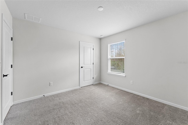 spare room featuring carpet flooring and a textured ceiling