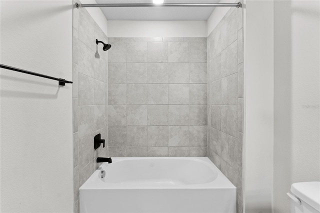 bathroom featuring toilet and tiled shower / bath