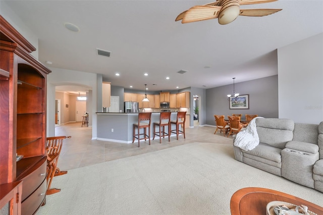 living room with ceiling fan with notable chandelier and light colored carpet