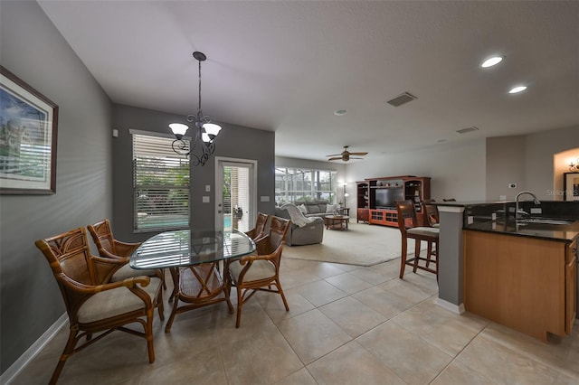 tiled dining space with ceiling fan with notable chandelier and sink