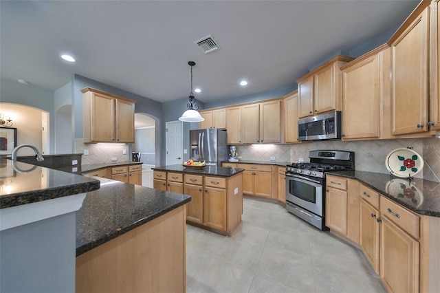 kitchen featuring appliances with stainless steel finishes, backsplash, decorative light fixtures, and a kitchen island