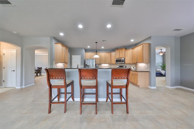 kitchen with ceiling fan, stainless steel appliances, a kitchen breakfast bar, pendant lighting, and a kitchen island