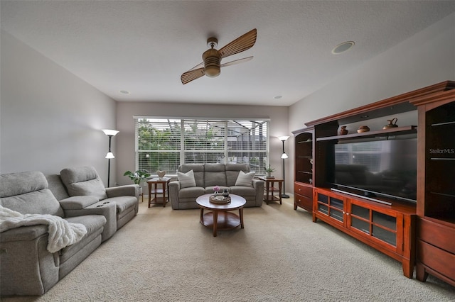 living room with ceiling fan, carpet floors, and a textured ceiling