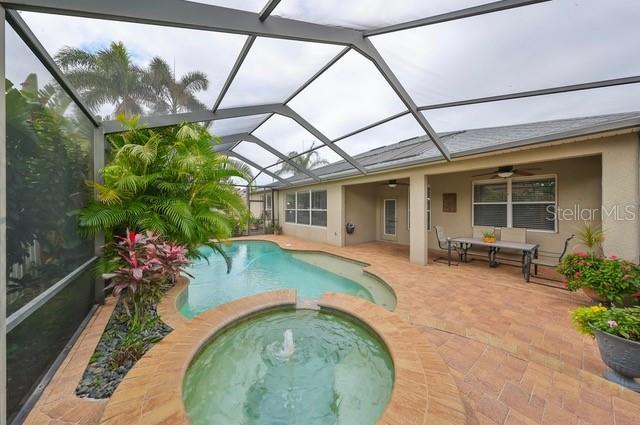 view of swimming pool featuring a lanai, ceiling fan, a patio area, and an in ground hot tub