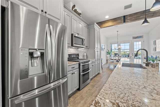 kitchen featuring beamed ceiling, light hardwood / wood-style floors, stainless steel appliances, and hanging light fixtures