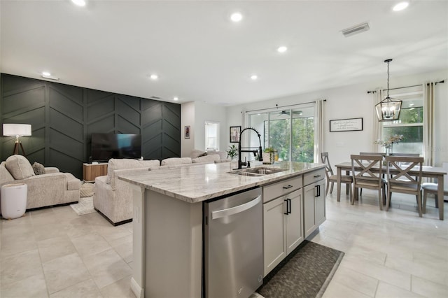 kitchen with white cabinetry, hanging light fixtures, light stone counters, stainless steel dishwasher, and a kitchen island with sink