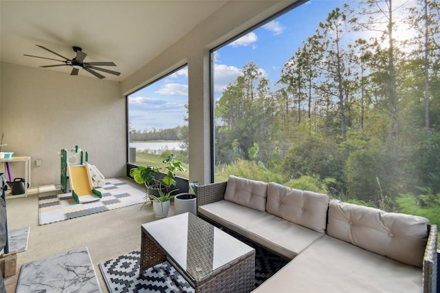 sunroom with ceiling fan and a water view