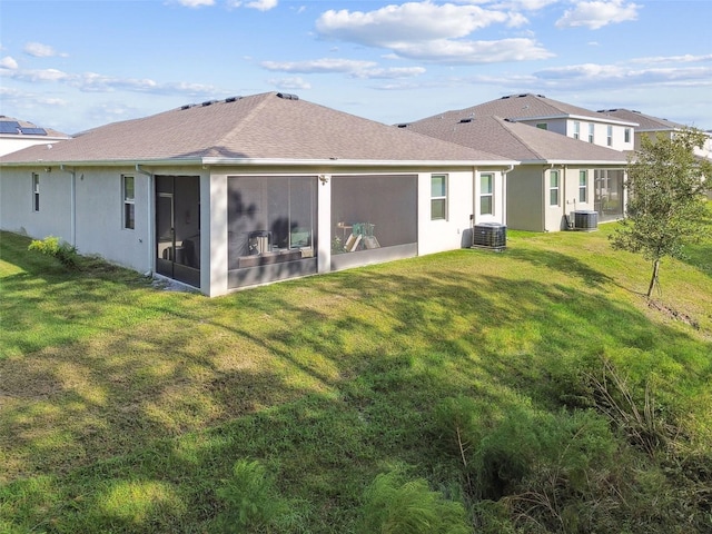 back of property with a sunroom, central AC unit, and a lawn