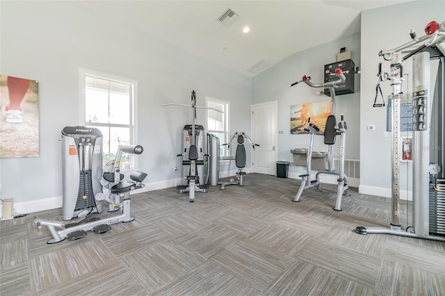 exercise room with light carpet and vaulted ceiling