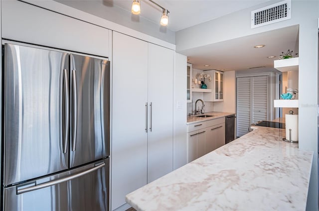 kitchen featuring white cabinets, appliances with stainless steel finishes, light stone counters, and sink