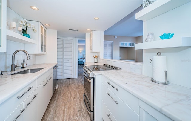 kitchen with light stone counters, stainless steel appliances, sink, light hardwood / wood-style flooring, and white cabinetry