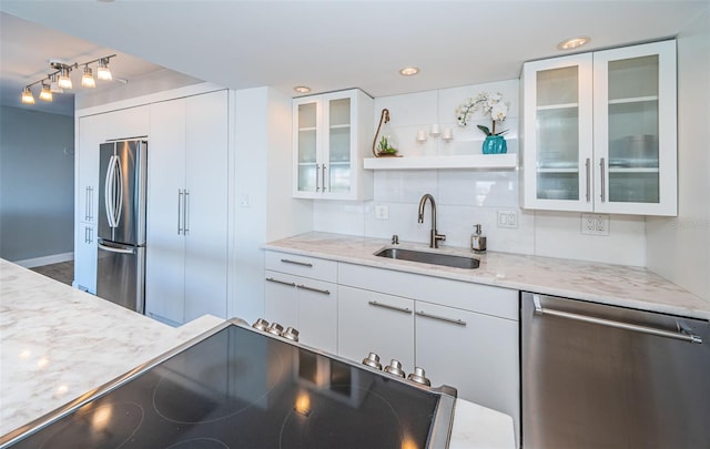 kitchen with sink, appliances with stainless steel finishes, tasteful backsplash, light stone counters, and white cabinetry