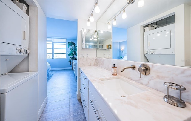 bathroom featuring tile patterned floors, vanity, stacked washer / dryer, and rail lighting